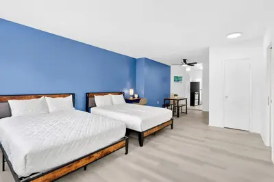 two beds in a room with a blue wall at Sunny Miami Beach Studio with 2 Queens plus Workspace in Miami Beach