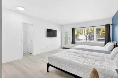 a white bedroom with two beds and a window at Sunny Miami Beach Studio with 2 Queens plus Workspace in Miami Beach