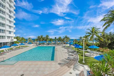 a resort pool with blue umbrellas and chairs at Miami Beach Studio with shared Heated Pool & Gym in Miami Beach