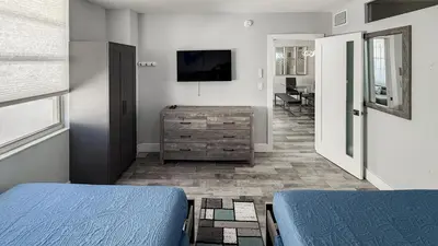 a bedroom with two beds and a dresser and a television at Great 2BR Condo-DIRECT BEACH ACCESS Pool, Gym and FREE Parking in Hollywood