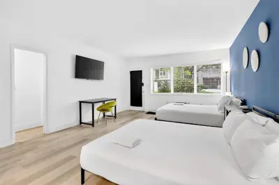 a hotel room with two beds and a desk at Cozy Miami Beach Studio with 2 Queens plus Workspace in Miami Beach