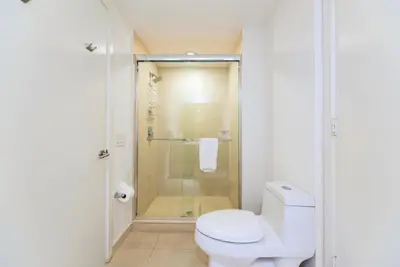a white bathroom with a shower and a toilet at Modern Beachside Condo W Ocean Views in Hollywood