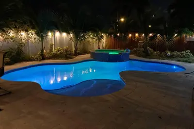 a swimming pool at night with a fountain at Private Luxe Pool Club Heated Spa in Fort Lauderdale
