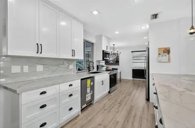 a white kitchen with white cabinets and a wooden floor at Spacious 3BR Home with Private Pool in Hollywood in Hollywood