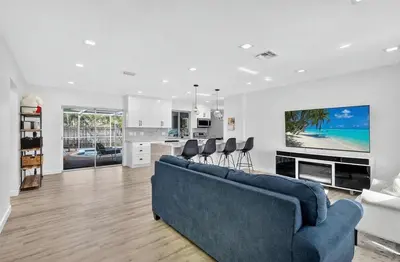 a living room with a blue couch and a kitchen at Spacious 3BR Home with Private Pool in Hollywood in Hollywood