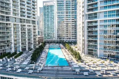 an overhead view of a swimming pool with lounge chairs and buildings at The Palazzo, Heart of Miami, Rooftop Pool, Lux Spa in Miami