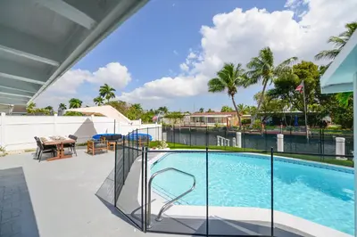 a swimming pool with a fence and a table and chairs at Waterfront Pool Home to Few Minutes to Beach in Fort Lauderdale