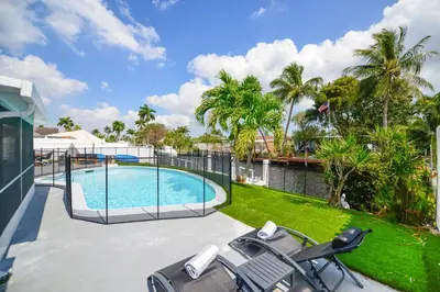 a swimming pool with two lawn chairs and trees at Waterfront Pool Home to Few Minutes to Beach in Fort Lauderdale