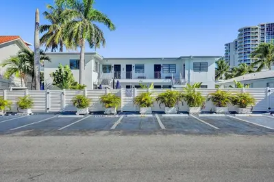 a white building with palm trees and a white fence at Desoto Beach Retreat with Heated Pool - By Atlantikos in Hollywood