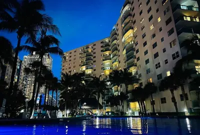 a pool with palm trees in front of buildings at The Tides on Hollywood Beach in Hollywood