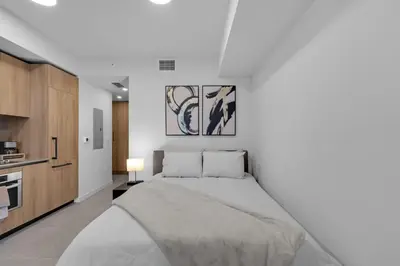 a white bedroom with a large bed and a kitchen at Brand New Modern Downtown Studio at Prime Location in Miami