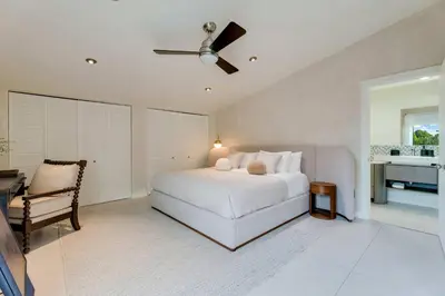 a white bedroom with a bed and a chair at Casa Anton- Artist Home Pool & Rooftop Hot Tub in Miami