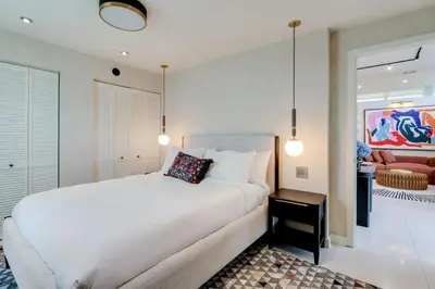 a bedroom with a large white bed and a living room at Casa Anton- Artist Home Pool & Rooftop Hot Tub in Miami