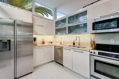 a kitchen with white cabinets and stainless steel appliances at Casa Anton- Artist Home Pool & Rooftop Hot Tub in Miami