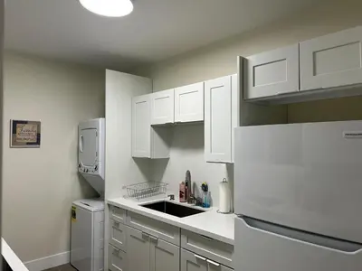 a kitchen with white cabinets and a white refrigerator at Spring Village by the Canal Loft in Miami