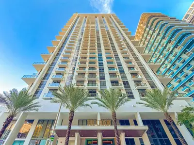 a tall building with palm trees in front of it at Modern MIA Worldcenter Studio with Balcony Pool & Gym in Miami