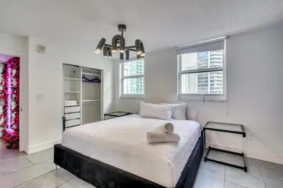 a bedroom with a bed and two tables and windows at Luxe Miami Vice Condo! Bay Views and Pool Access in Miami