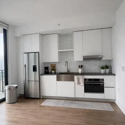 a kitchen with white cabinets and a stainless steel refrigerator at Prime Miami location - Modern Skyline Stay in Miami