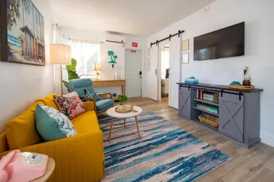 a living room with a yellow couch and a table at Tropical Retreat with Private Yard, Fire Pit, Hammock in Hollywood