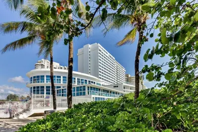 a large building with palm trees in front of it at Castle Beach Club Apartments in Miami Beach