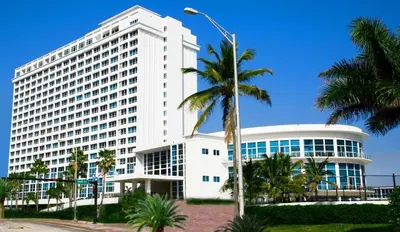a large white building with palm trees in front of it at Castle Beach Club Apartments in Miami Beach