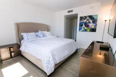 a white bedroom with a bed and a dresser at Beachwalk Resort Residence in Hollywood