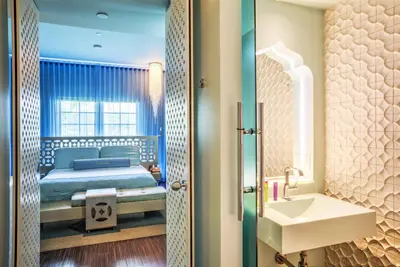 a bedroom with a bed and a sink and a mirror at Dream South Beach, by Hyatt in Miami Beach