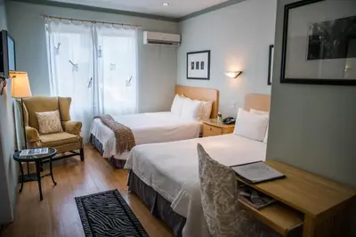 a hotel room with two beds and a chair at Cadet Hotel in Miami Beach