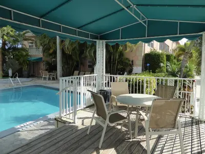a patio with a table and chairs next to a pool at PlayaBlanco Suites in Fort Lauderdale