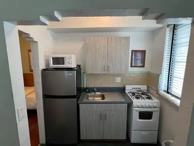 a small kitchen with a stove and a microwave at Sherbrooke All Suites Hotel in Miami Beach
