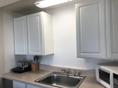 a kitchen with white cabinets and a sink at Beach Place Hotel in Miami Beach