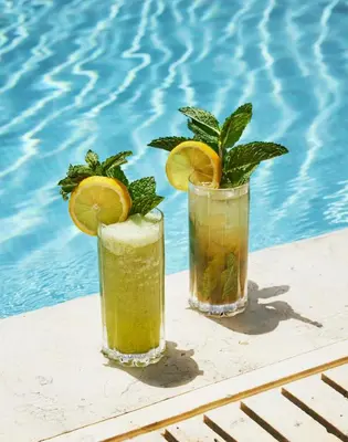 two cocktails sitting on a table next to a swimming pool at The Setai, Miami Beach in Miami Beach