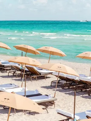 a group of beach chairs and umbrellas on a beach at The Setai, Miami Beach in Miami Beach