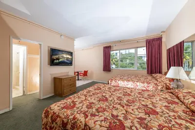 a hotel room with two beds and a desk at Geneva Hotel in Miami Beach