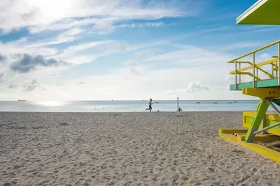 a beach with a lifeguard tower and people on the beach at Geneva Hotel in Miami Beach