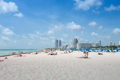 a group of people sitting on a beach at Geneva Hotel in Miami Beach