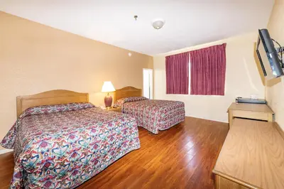 a hotel room with two beds and a flat screen tv at Geneva Hotel in Miami Beach