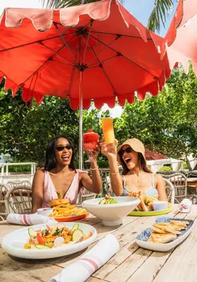 two women sitting at a table with food and an umbrella at Cadillac Hotel & Beach Club, Autograph Collection in Miami Beach