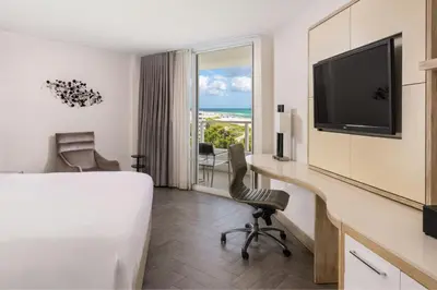 a hotel room with a bed and a desk with a television at Marriott Stanton South Beach in Miami Beach