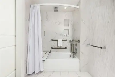 a white bathroom with a tub and a shower curtain at Marriott Stanton South Beach in Miami Beach