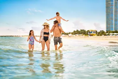 a family walking in the water on the beach at Marriott Stanton South Beach in Miami Beach
