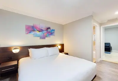 a bedroom with a white bed and a painting on the wall at Nuvo Suites Hotel - Miami Doral in Miami