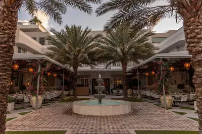 a courtyard with palm trees and a fountain in front of a building at Liberty Park Hotel South Beach in Miami Beach