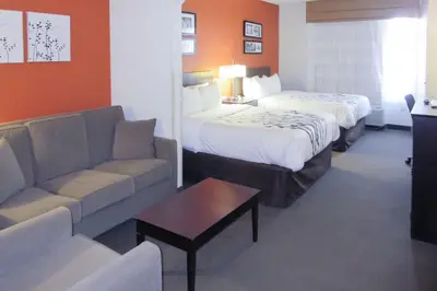 a hotel room with two beds and a couch at Sleep Inn & Suites Ft Lauderdale International Airport in Dania Beach