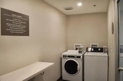 a laundry room with a washing machine and a sign at Best Western Plus Ft Lauderdale Hollywood Airport Hotel in Hollywood