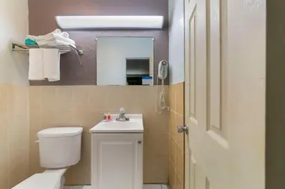 a bathroom with a toilet and a sink and a mirror at Fort Lauderdale Gardens Inn & Suites Ft Lauderdale International Airport in Hollywood