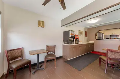 a waiting room with a table and chairs and a kitchen at Fort Lauderdale Gardens Inn & Suites Ft Lauderdale International Airport in Hollywood