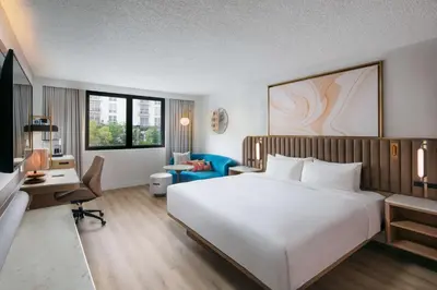 a hotel room with a large white bed and a desk at Sonesta Miami Airport in Miami