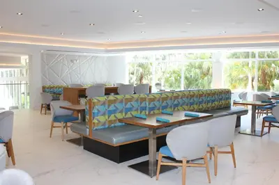 a dining room with tables and chairs and windows at Holiday Inn Miami Beach-Oceanfront by IHG in Miami Beach