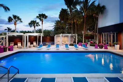 a swimming pool with lounge chairs and a hotel at Aloft Miami Dadeland in Kendall
